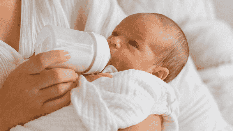 A newborn baby showing hunger cues by rooting and turning head with mouth open