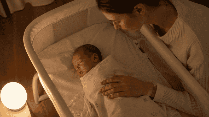 A newborn baby being bottle-fed by a parent, showing a close-up of the baby's face and the bottle