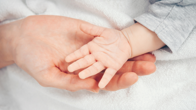A close-up of a newborn baby showing early sleepy cues like rubbing eyes and slight redness around the eyebrows, helping parents identify wake window endings.