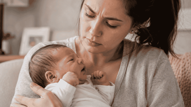 A concerned parent checking on their newborn baby after a forceful spit-up episode at home