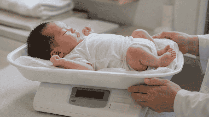 A tired mother nursing her baby more frequently than usual during a growth spurt at home