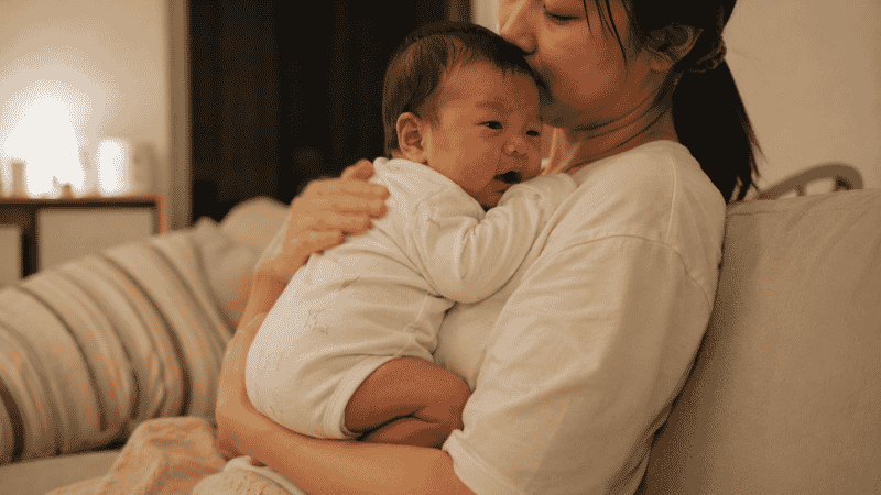 A parent gently holding a gassy newborn baby against their chest, trying to comfort and relieve gas pain