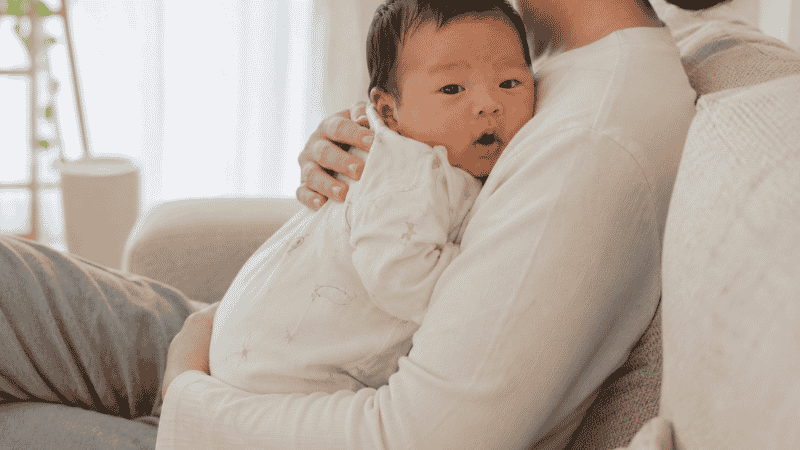 A parent holding their newborn baby in an upright position for 20 to 30 minutes after feeding to prevent hiccups
