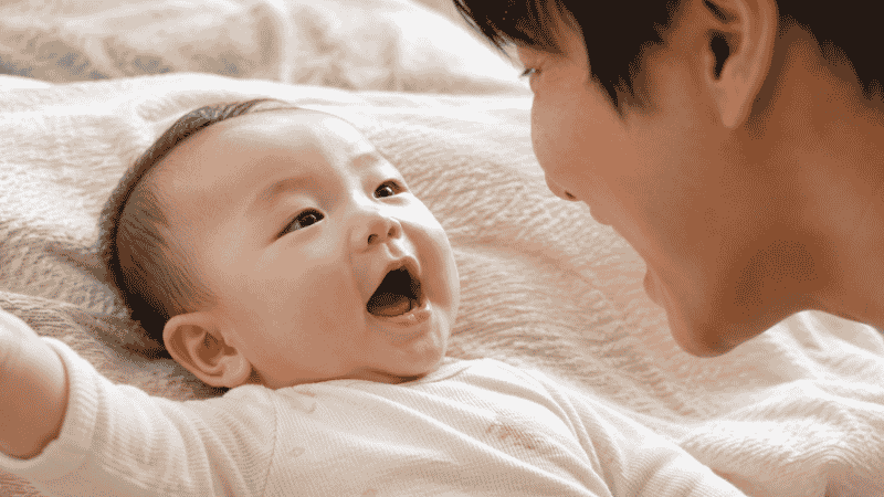 A 5 month old baby making sounds and babbling with an open mouth and happy expression during early speech development