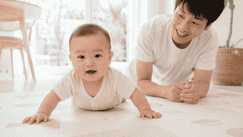A baby doing tummy time and pushing up on straight arms to build the shoulder and core strength needed for crawling