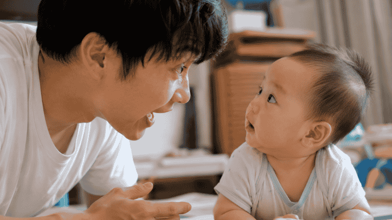 A parent talking animatedly to their baby face-to-face, encouraging early speech and language development