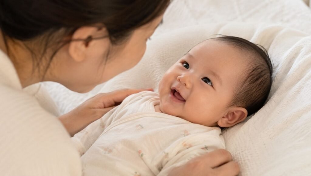A newborn baby making eye contact and giving a first social smile to a parent at around 6 to 8 weeks old